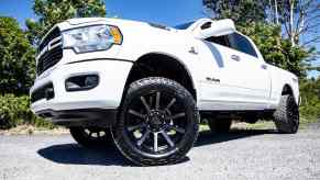 The aftermarket rims under a lifted white Ram pickup truck parked in a lot.