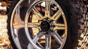 Spiked lug nuts and chrome rim beneath a lifted pickup truck.