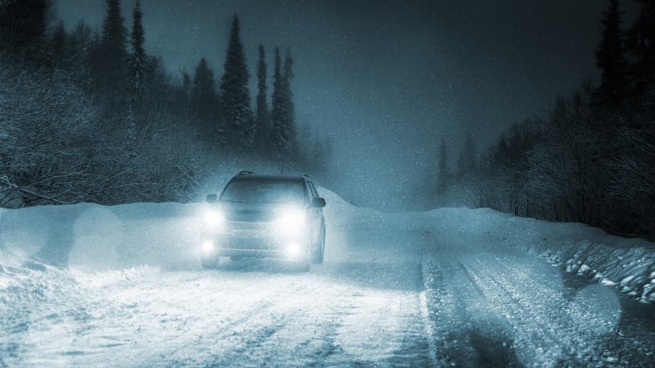 SUV Driving In Winter Weather at night. There could be black ice on the road.