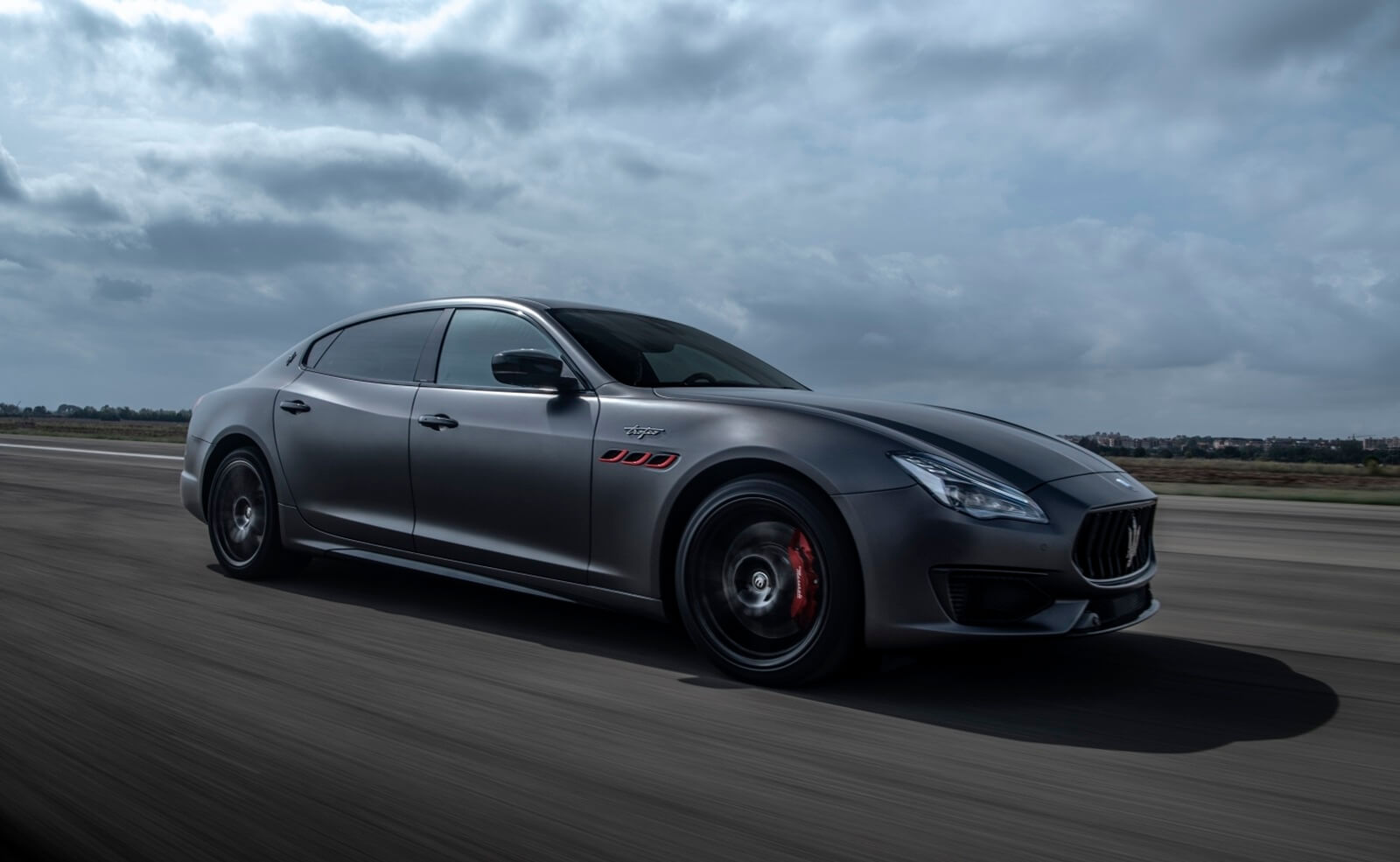 A black Maserati Quattroporte cruises on an open track 