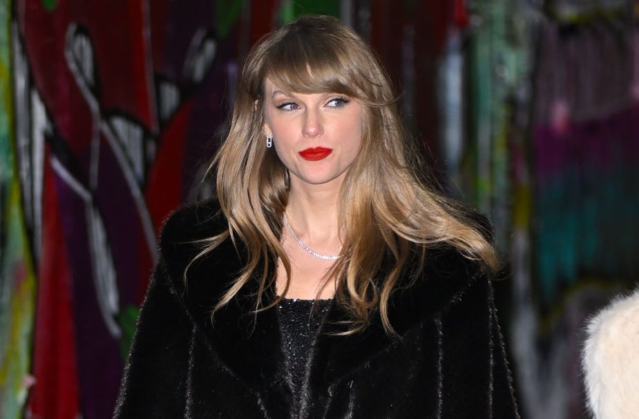 Taylor Swift leaves an event in a dark coat.