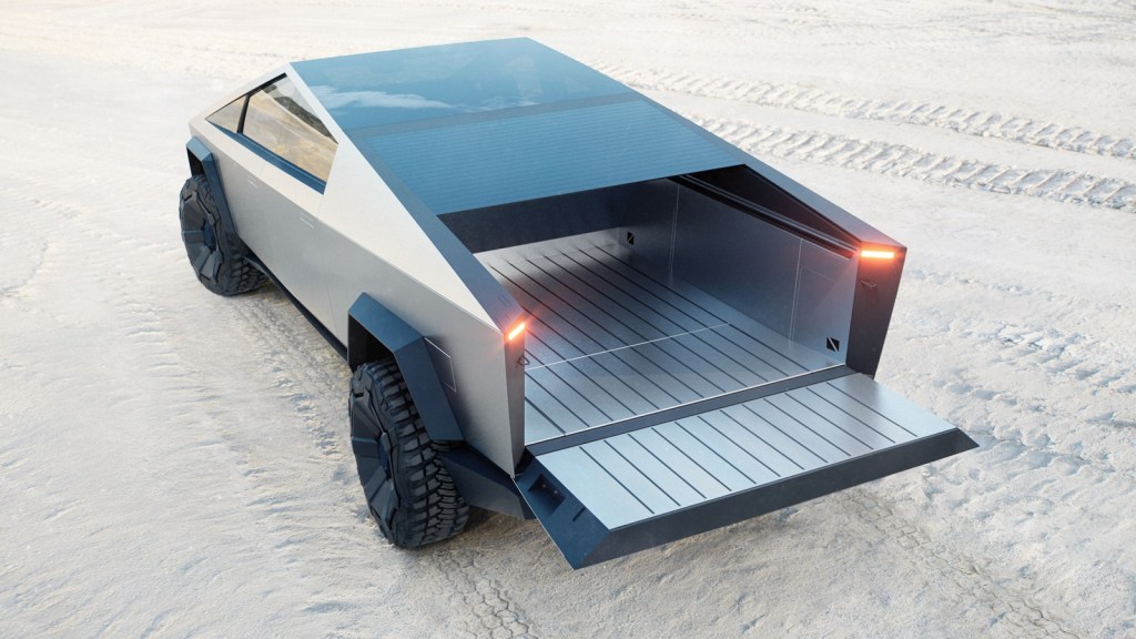 The back of a Tesla Cybertruck parked on a sandy beach with its tailgate down.