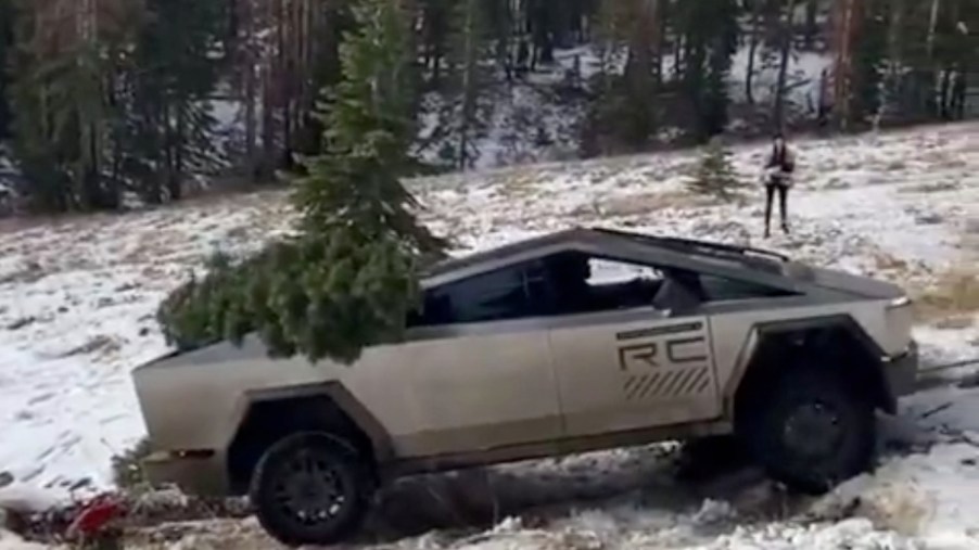 Prototype Tesla Cybertruck carrying a Christmas tree up a snowy hill.