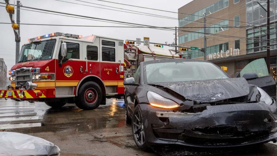 Crashed Tesla vehicle with autopilot with a firetruck visible in the background.