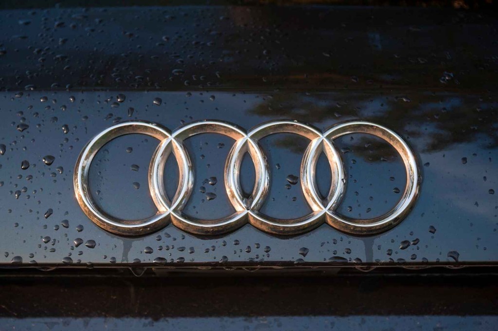 Audi emblem in close view on a black car with water droplets