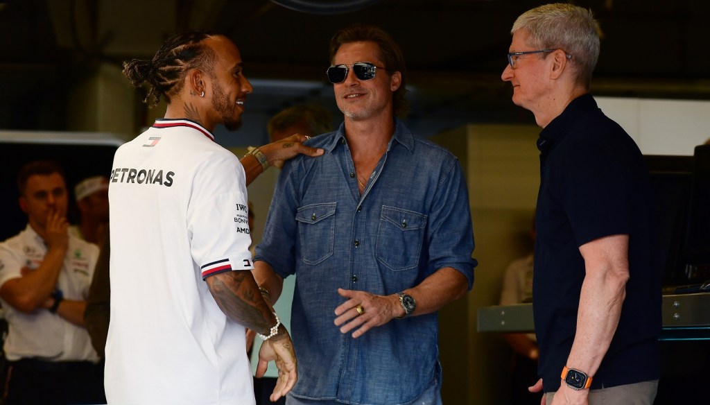 Lewis Hamilton puts his hand on Brad Pitt's shoulder facing each other smiling