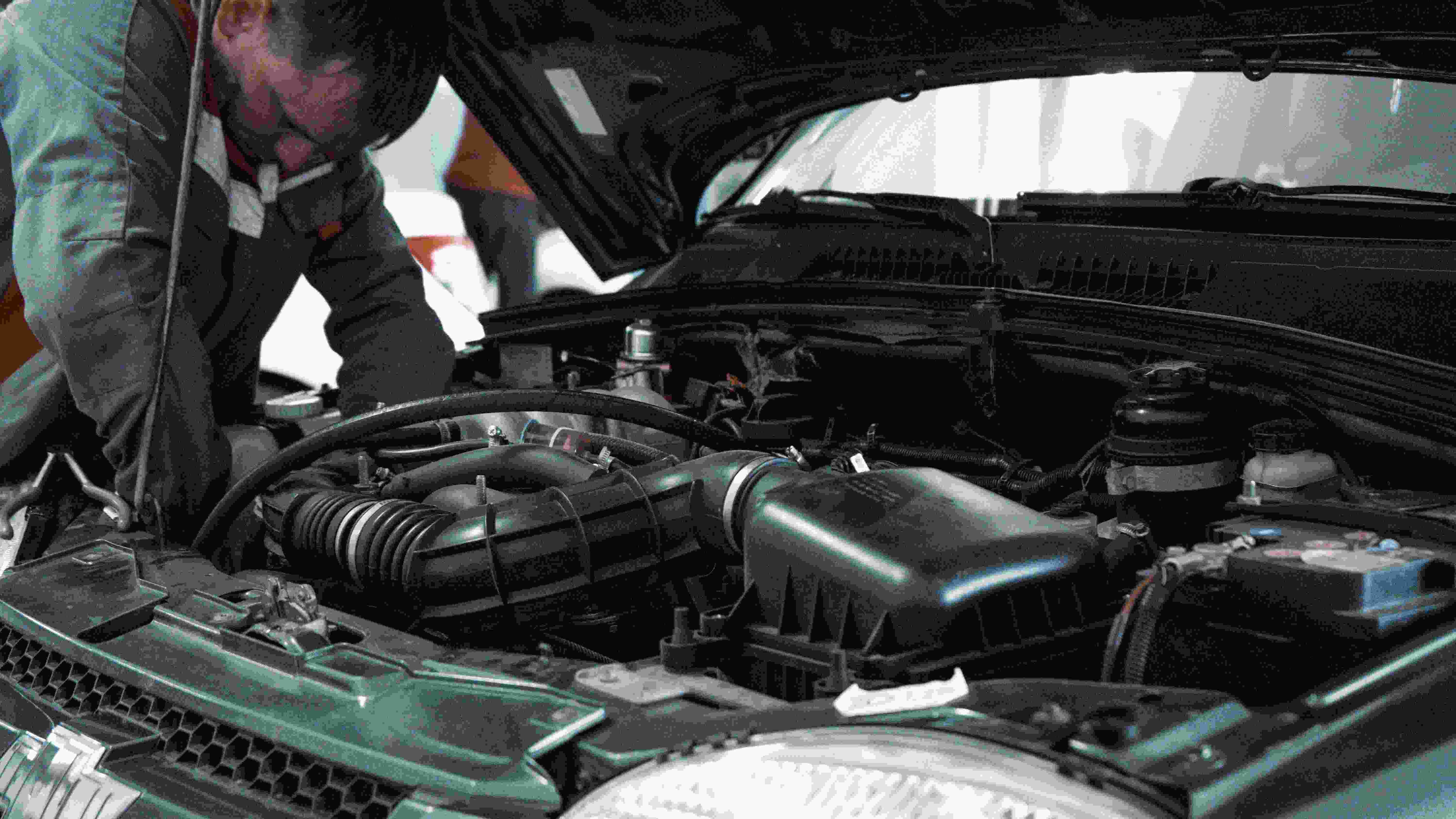 A mechanic works under the hood of a car