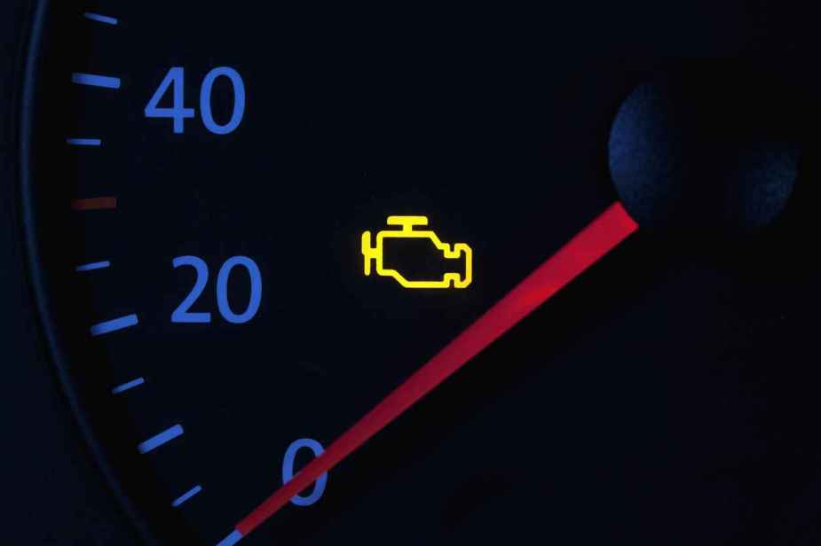 A yellow check engine fault icon is shown illuminated on a speedometer