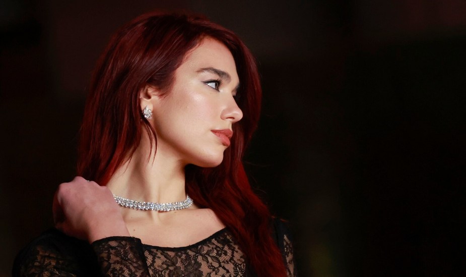 Dua Lipa attends the 3rd Annual Academy Museum Gala at the Academy Museum of Motion Pictures in Los Angeles, December 3, 2023, wearing a diamond necklace, black lace dress, and long red hair.