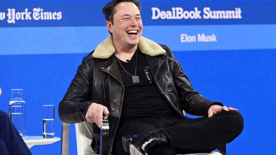 Elon Musk laughing while sitting at the 2023 New York Times DealBook Summit