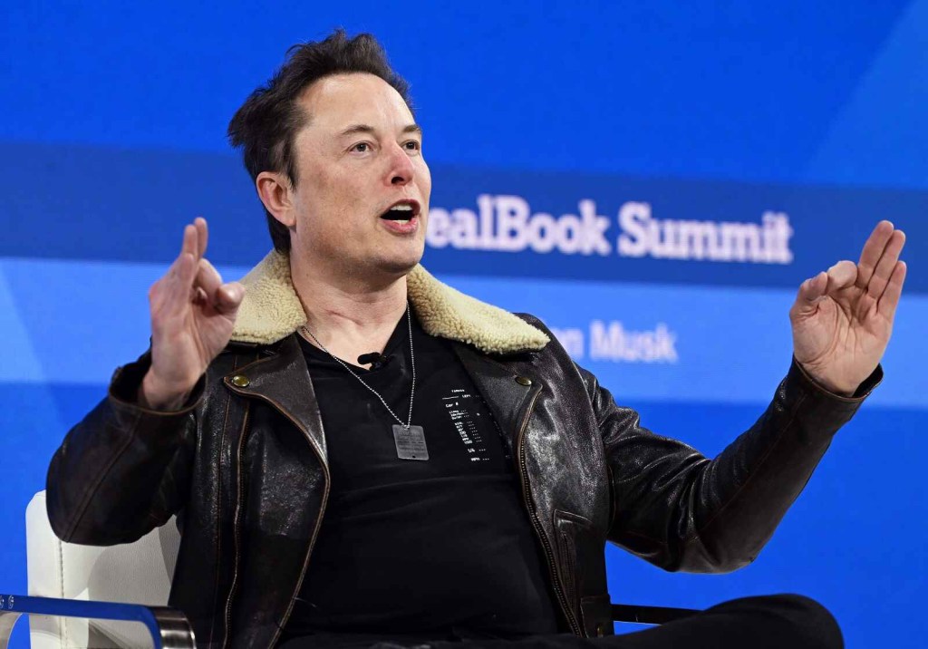 Elon Musk gestures with both hands while speaking at the 2023 New York Times DealBook Summit