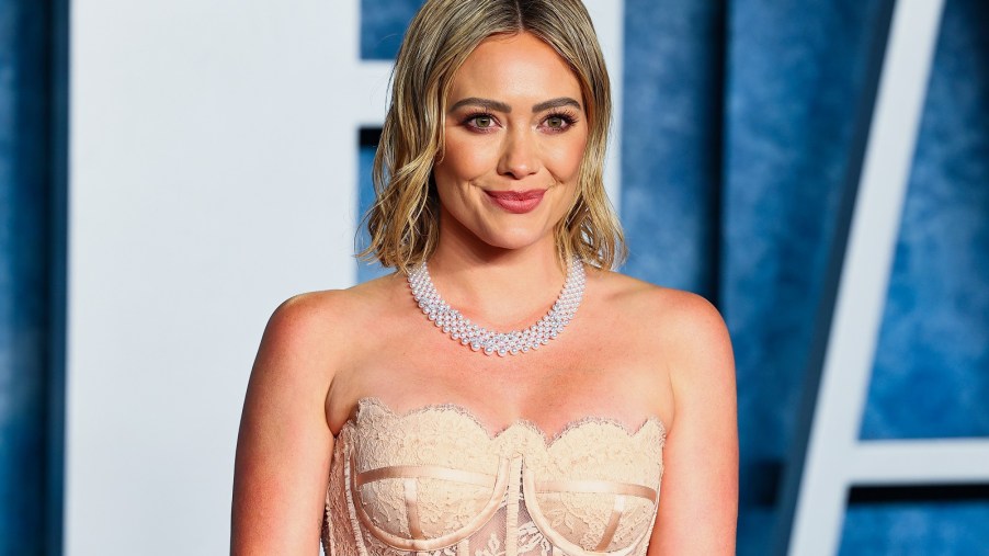 Hilary Duff attends an event wearing a satin gold lace corseted gown and diamond necklace