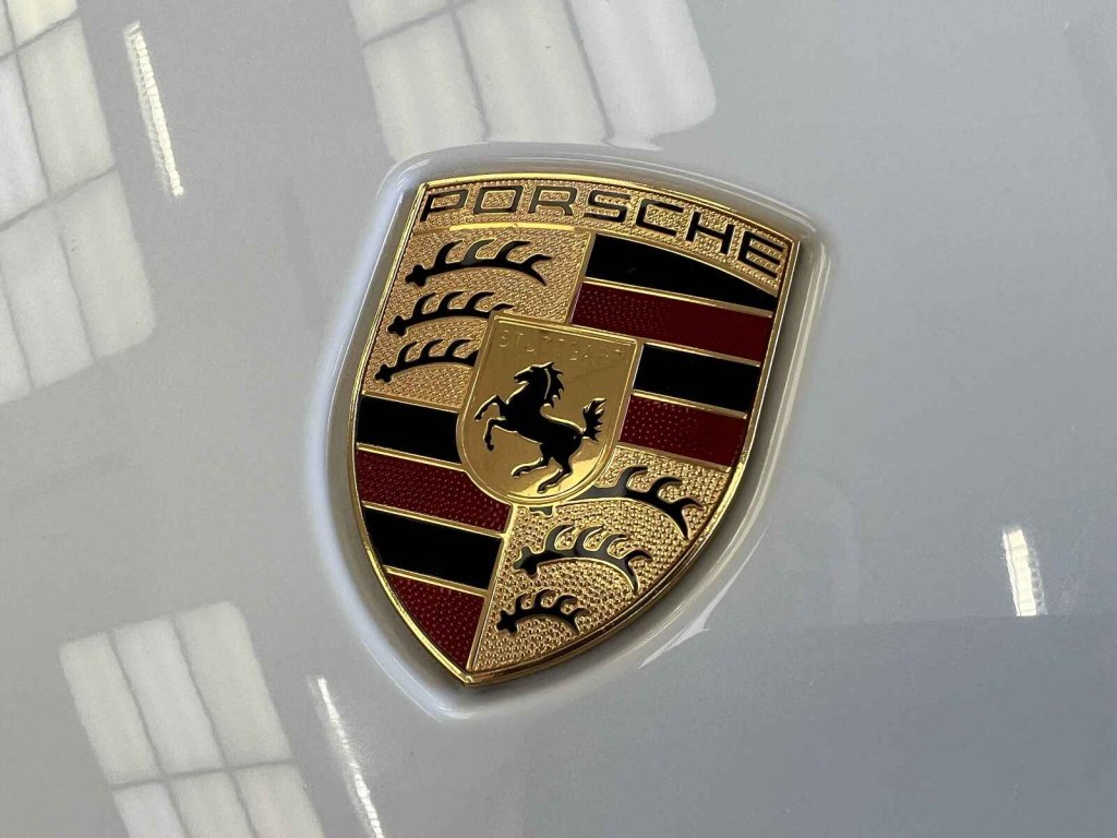 A Porsche emblem is shown on a white car hood