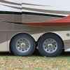 RV axles are shown in close exterior view, four RV wheels in profile view parked on grass