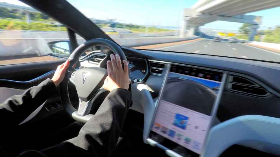 A person's hands are shown driving a Tesla Model X featuring autopilot