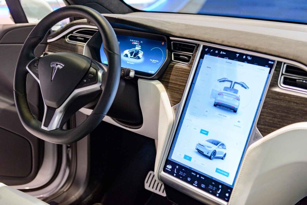 A Tesla Model X interior dash with screen displaying the full vehicle views