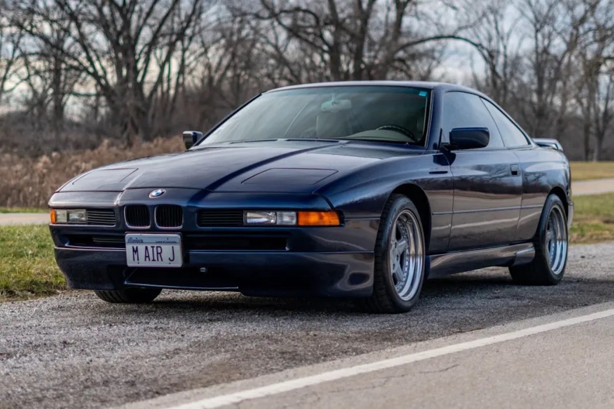 Blue grand touring coupe by BMW, parked on the road with trees visible in the background.