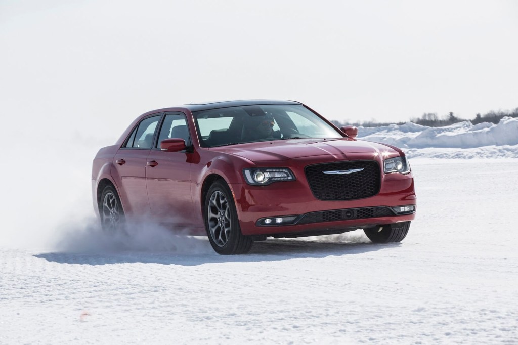 A used, red 2015 Chrysler 300 AWD kicks up snow. 