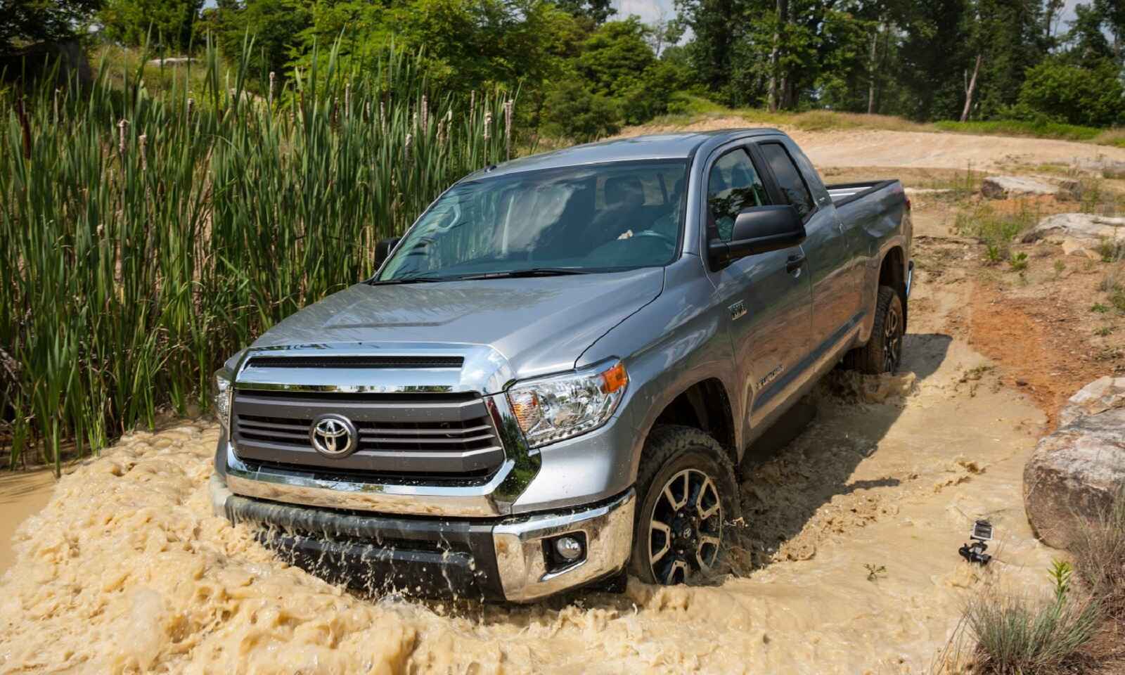 A silver 2016 Toyota Tundra drives down a watery incline