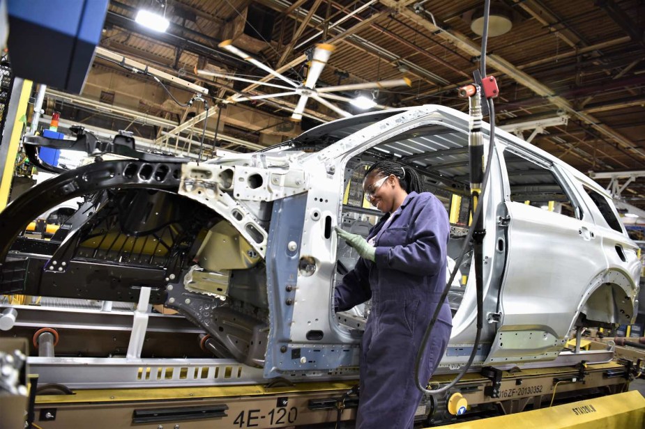 A factory worker assembles a Ford Explorer full-size SUV