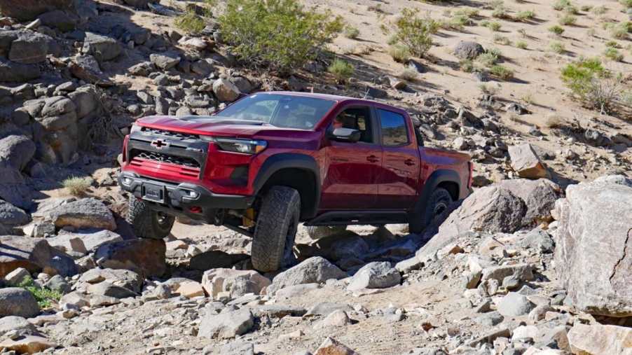 Red 2024 Chevrolet Colorado ZR2 Bison midsize truck crawling over rocks.