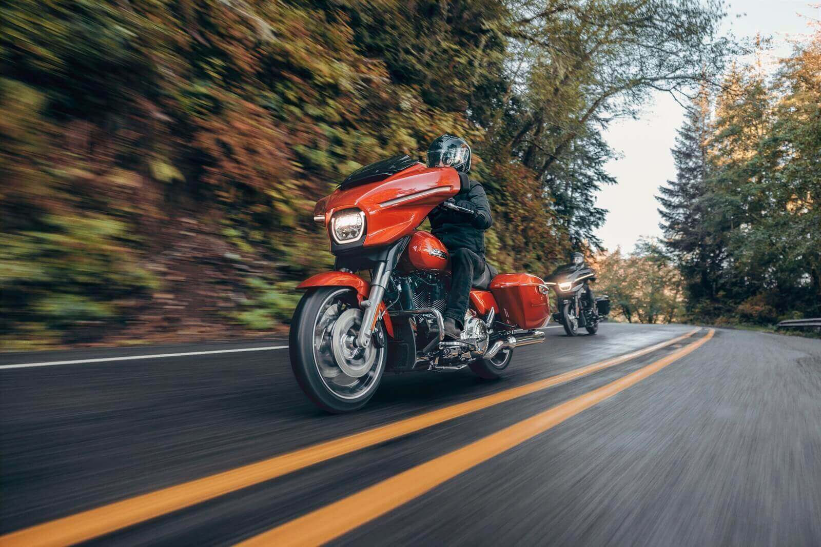 An orange and black set of 2024 Harley-Davidson Street Glides tackle a wet road. 