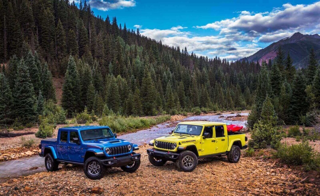 A set of blue and a yellow Jeep Gladiators, two of Stellantis' vehicles with the most expensive maintenance costs, sit by a creek. 