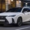 White 2024 Lexus UX Hybrid on a city street. This luxury SUV is an efficient option.