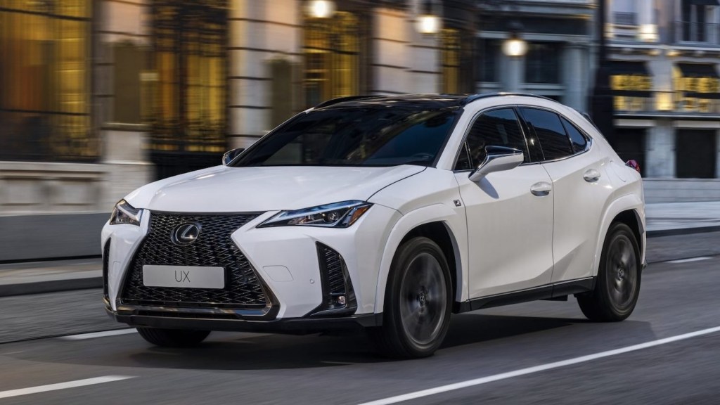 White 2024 Lexus UX Hybrid on a city street. This luxury SUV is an efficient option.