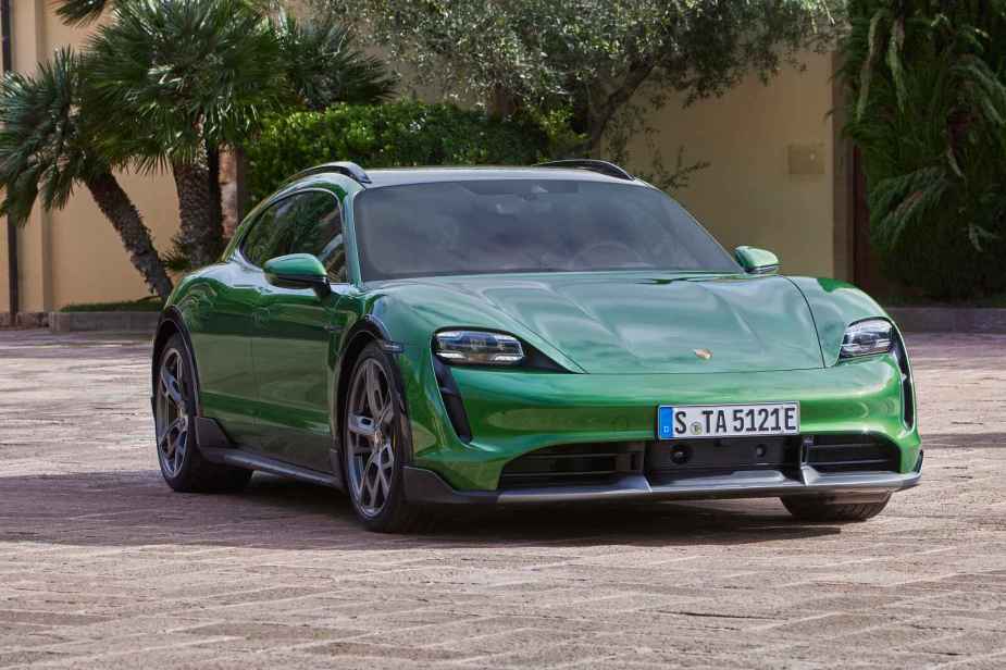 A green 2024 Porsche Taycan Turismo parked on paverstones