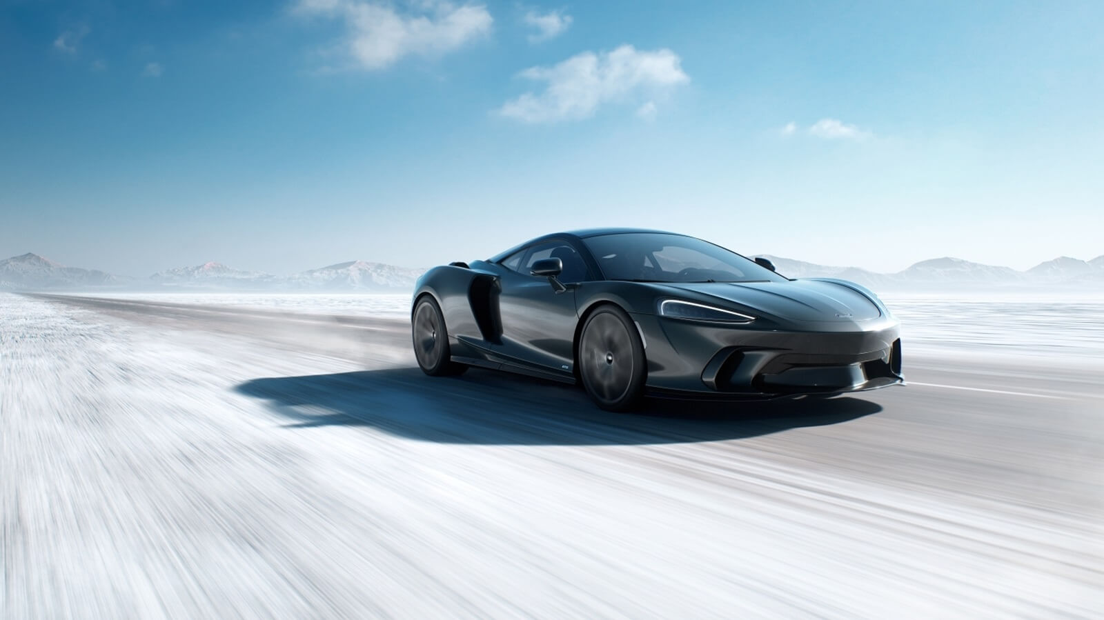 A 2025 McLaren GTS kicks up dust as it speeds on a salt flat.