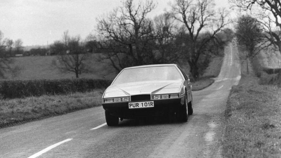 A classic 1976 Aston Martin Lagonda cruises down an English road.