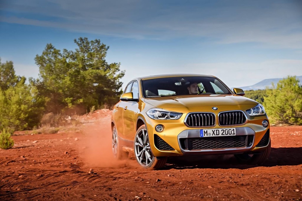 A gold BMW X2, one of the car colors with the worst depreciation, kicks up dirt. 
