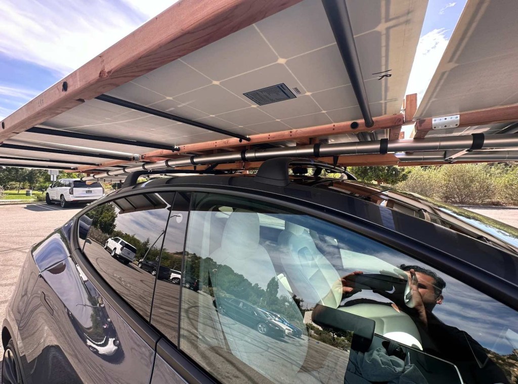 The wood and carbon fiber frame under a solar panel array on the roof of a Tesla Model Y