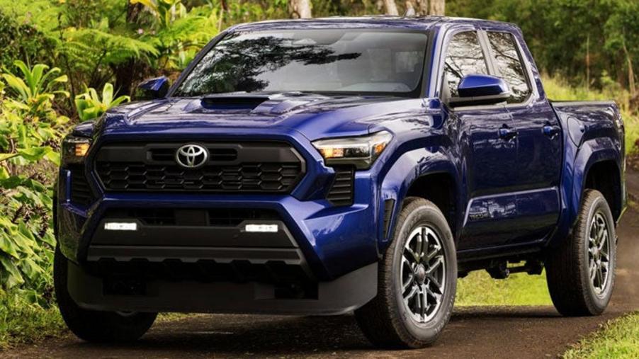 Blue 2024 Toyota Tacoma midize truck driving on a dirt road