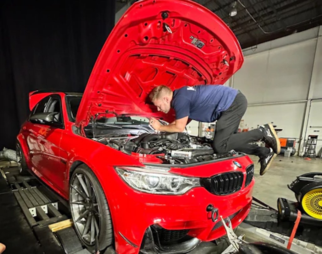 Brian Kiefer under the hood of his red 2016 BMW M3 sedan
