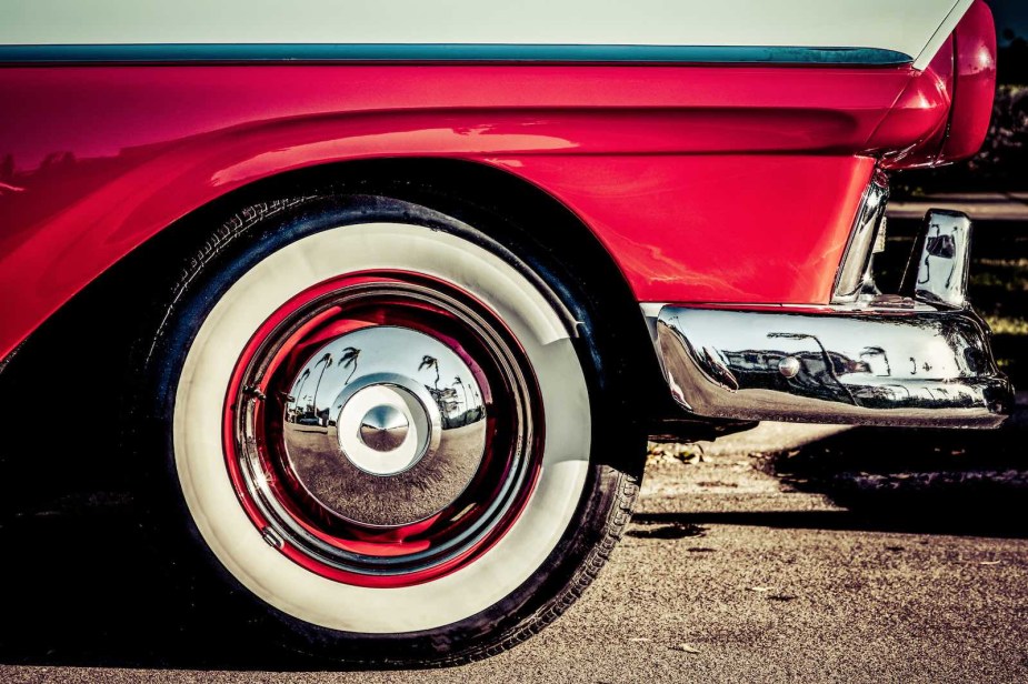 Chrome hubcap of a classic car reflecting California palm trees.