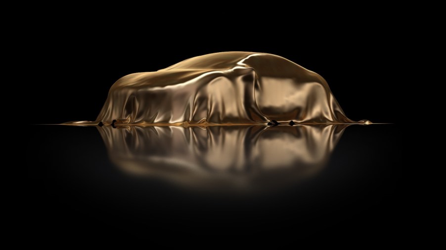 Sweepstakes prize car under a gold cover on a black stage.