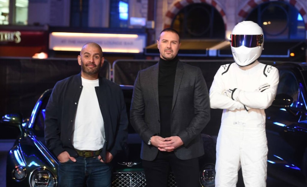 Chris Harris, left, stands alongside Paddy McGuinness and the Stig, reviewers of Ferraris and other supercars, at an event. 