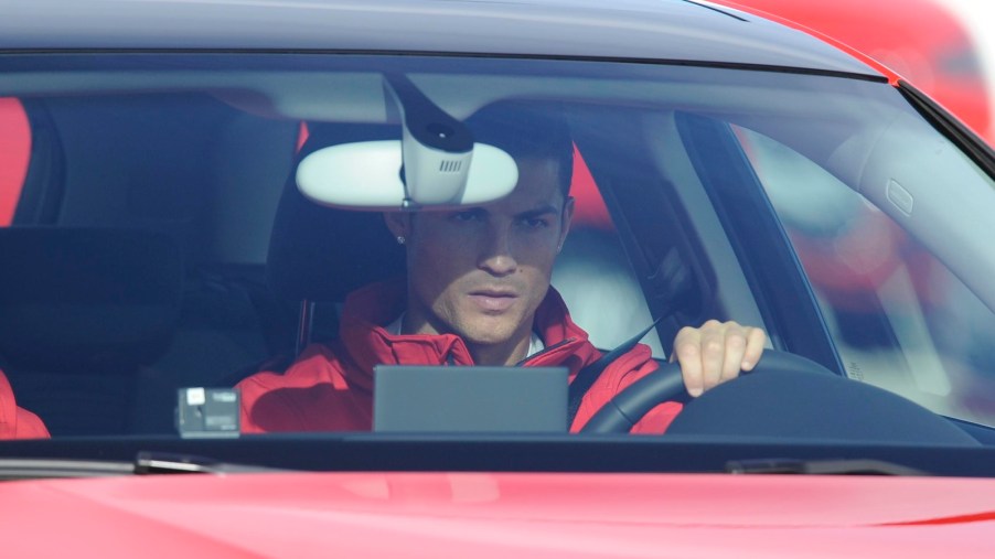 Soccer superstar Cristiano Ronaldo behind the wheel of a red sports car.