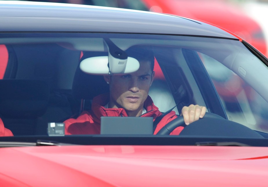 Soccer superstar Cristiano Ronaldo behind the wheel of a red sports car.