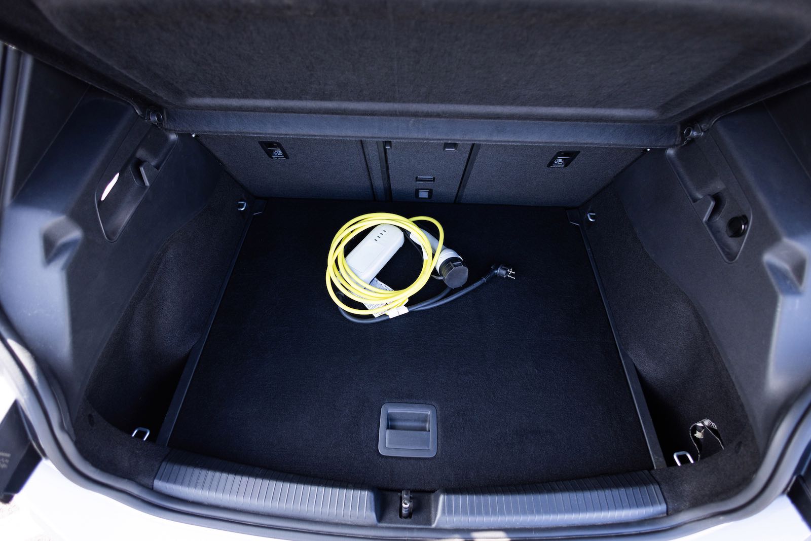 The front trunk, or frunk, of a Tesla car with a charging cable coiled inside.