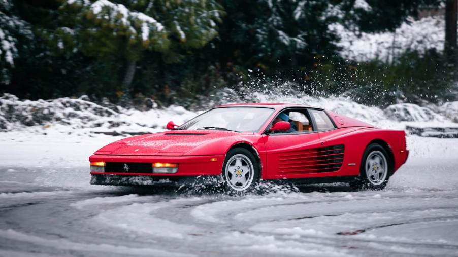 A red Ferrari Testarossa rear-wheel drive supercar drives through the snow.