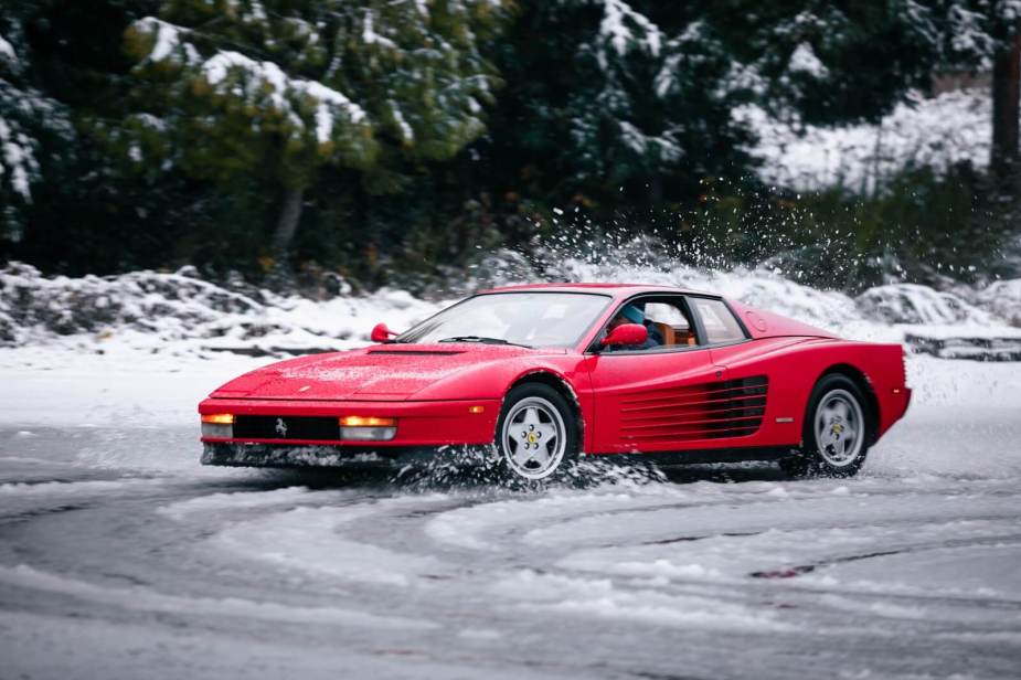 A red Ferrari Testarossa rear-wheel drive supercar drives through the snow.