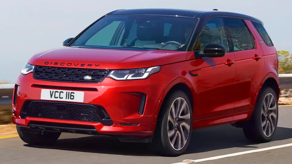 Red Land Rover Discovery Sport driving on a road. This might be a good off-road SUV, but not great as a luxury vehicle in terms of cost of ownership.