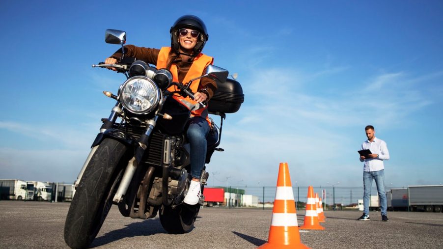 A smiling motorcycle rider takes on a course for licensing.