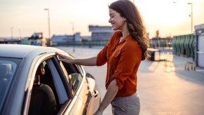 Woman stands next to a new car she's buying to check the manufacturer date