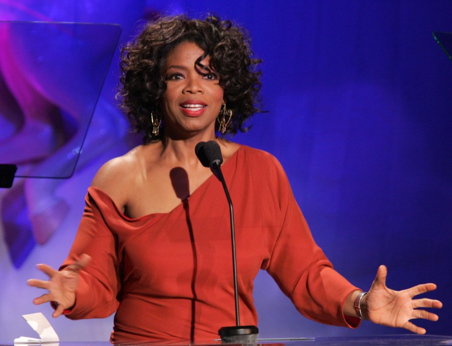 Oprah Winfrey stands behind a podium and speaks into a microphone.