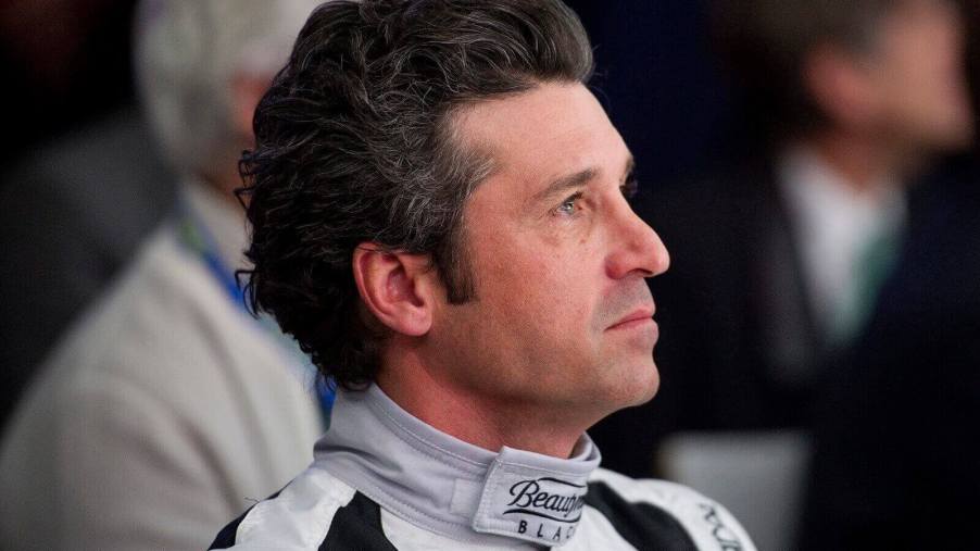 Patrick Dempsey, racing driver and actor, looks away in a racing suit.