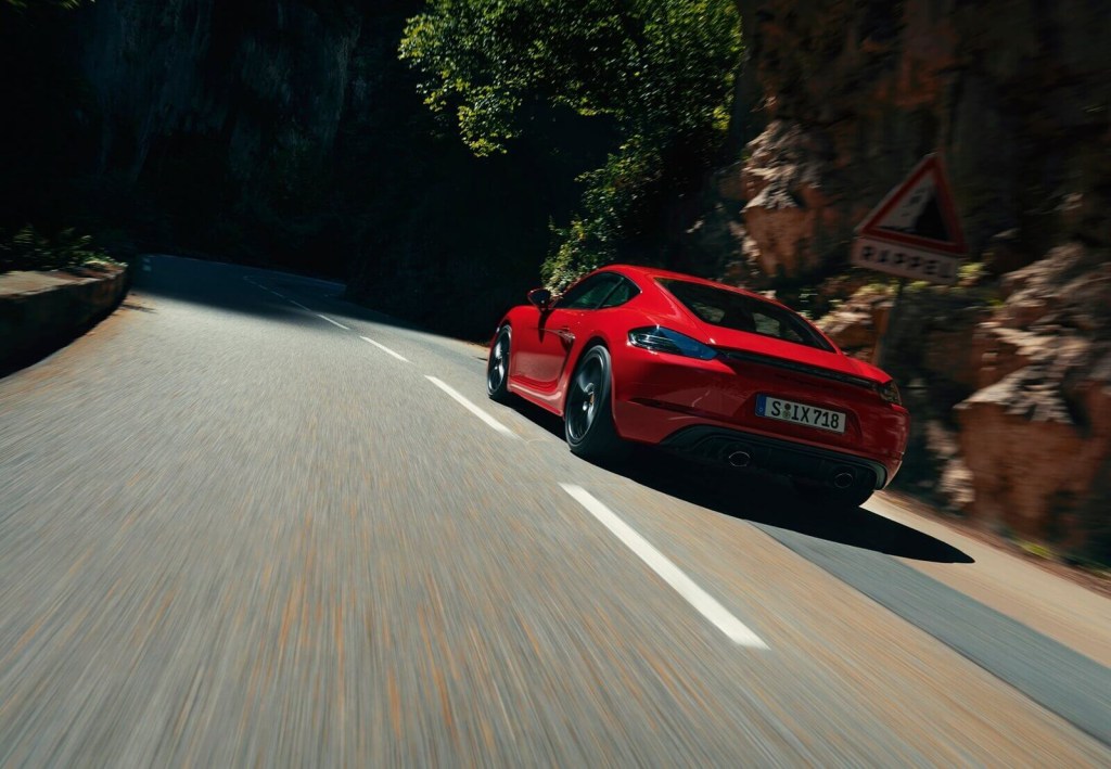 A red Porsche 718 Cayman GTS drives on a mountain road. 